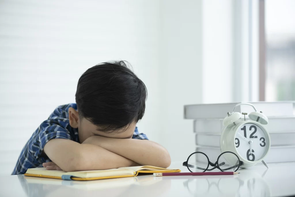 sad boy with his body slouched forward on a school desk