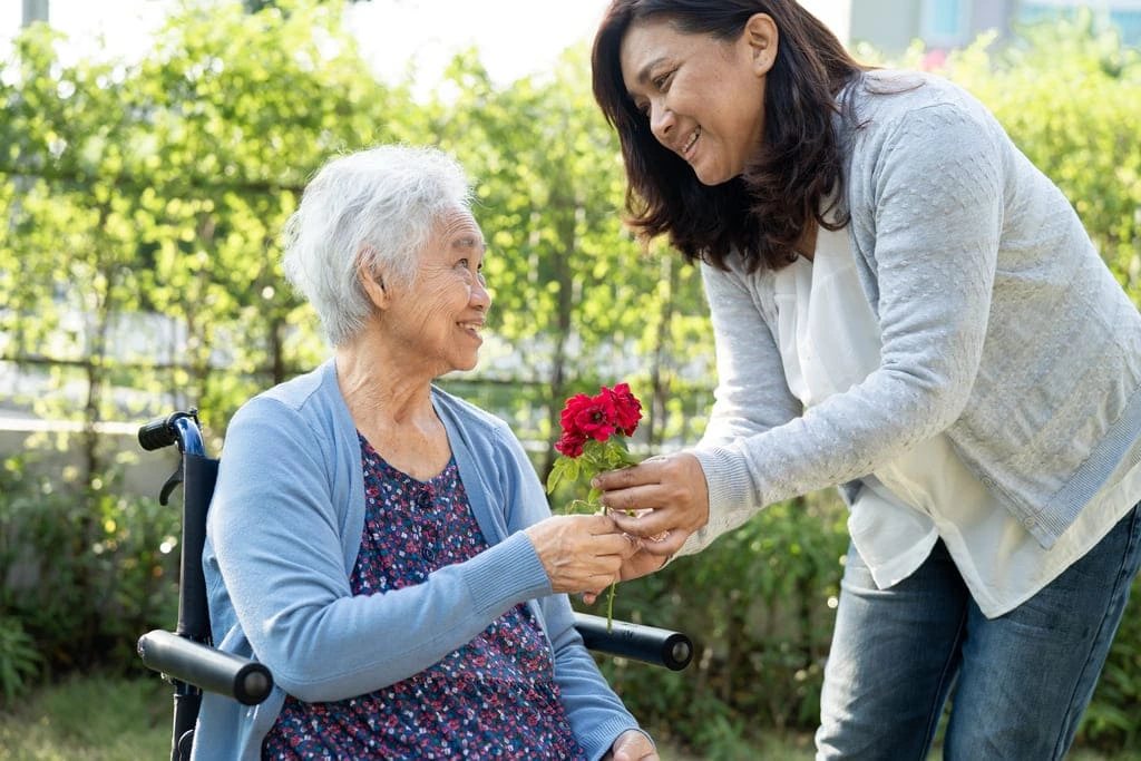 support worker gives flower to an elderly lady