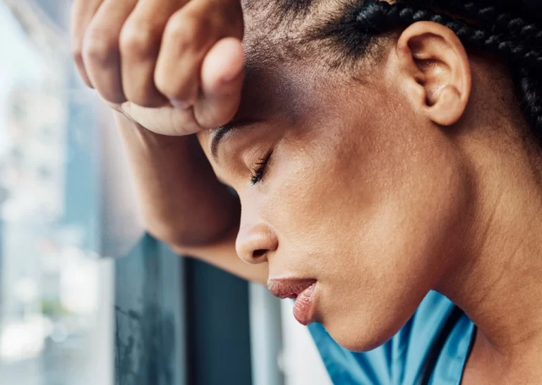 tired nurse leaning her head on a glass window