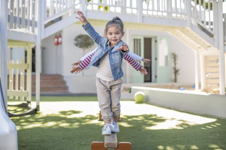 a little girl walking on a plank in a park
