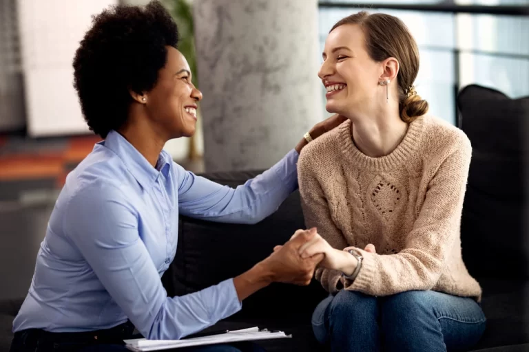 caregiver holding hands with a young girl and smiling