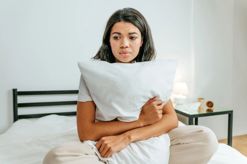 woman experiencing autistic burnout hugging a pillow in bed