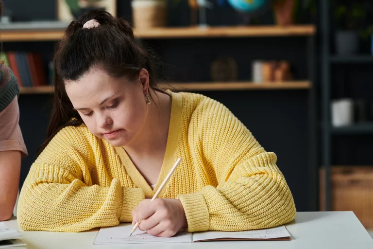 down syndrome girl writing in a notebook