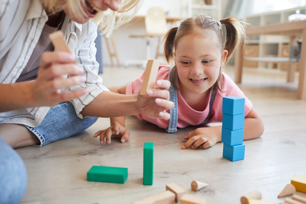 learning support worker playing with blocks with a down syndrome kid