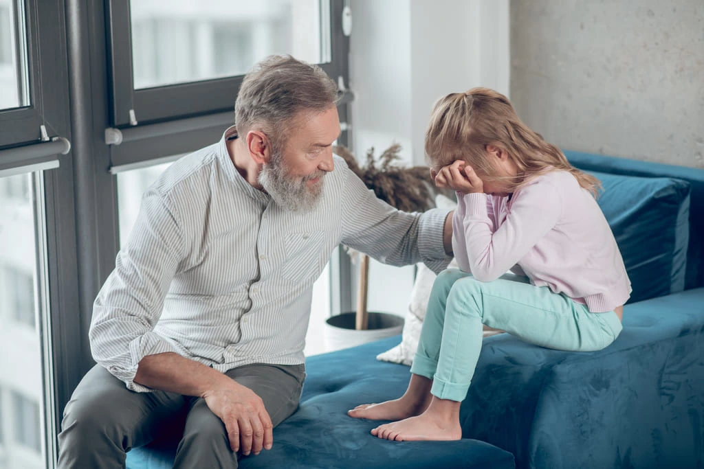 autistic girl crying on sofa and her dad comforting her