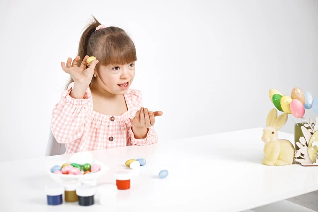 little girl with down syndrome sitting and playing with Easter eggs