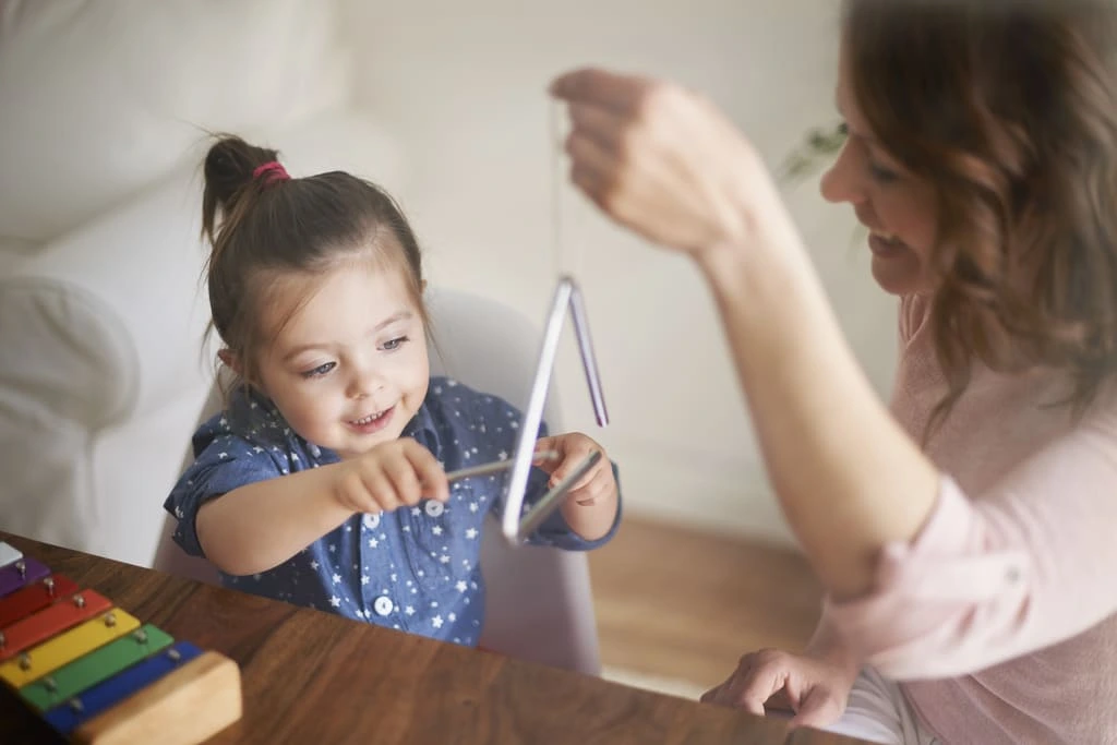 little girl playing with a triangle