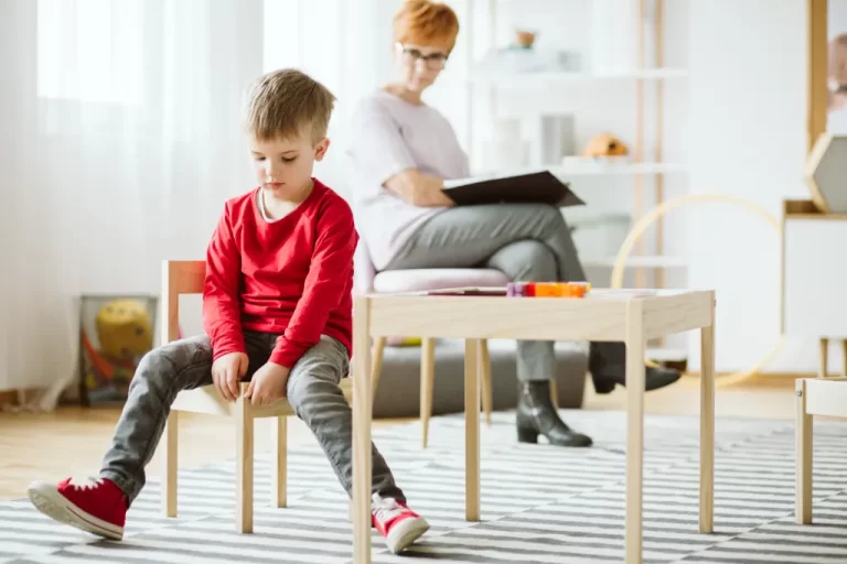 a boy sitting on a chair ignoring the caregiver