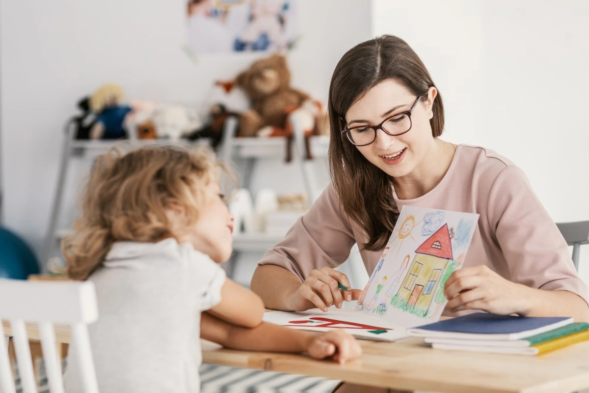 a caregiver holding a drawing by an autistic little girl