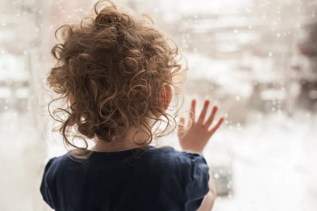 a little girl looking through a window glass