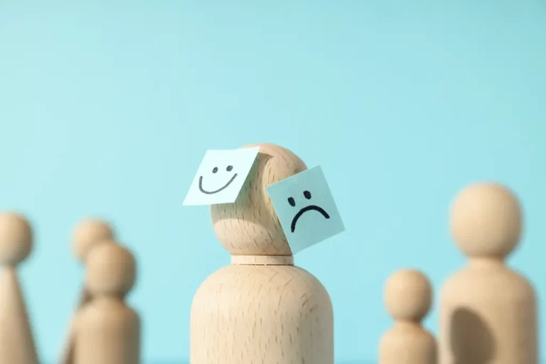 little wooden human shape figure with stickers with sad and happy faces