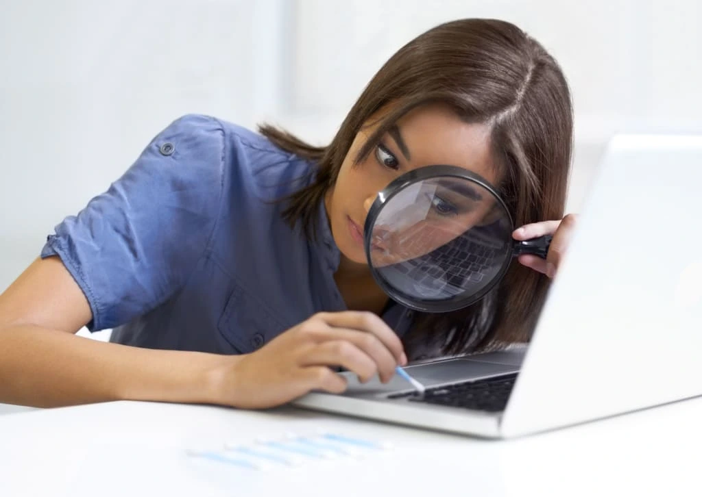 woman cleaning her laptop with a magnifying glass