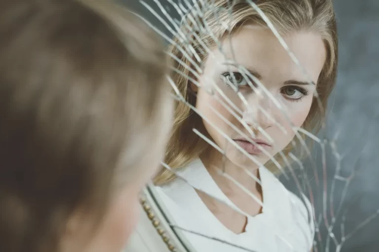girl looking at a scratched mirror with her reflection