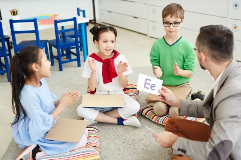 children with a speech and language therapist sitting and learning letters