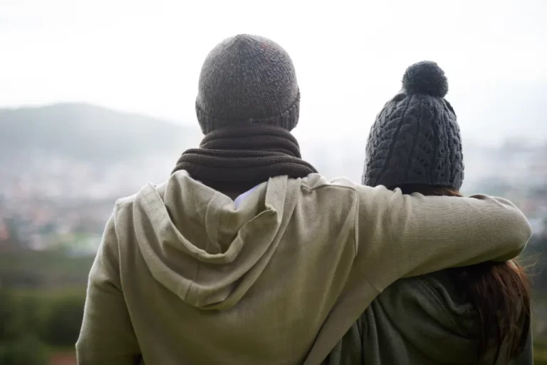 man with his arm around his girlfriend looking at a distance