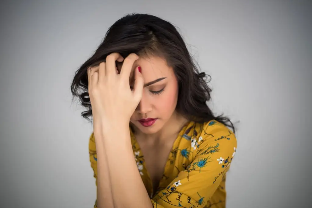 woman holding her forehead experiencing bpd splitting episode