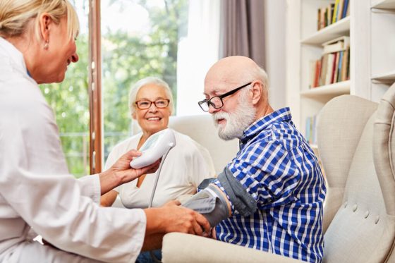 live-in carer measuring the blood pressure of an old man