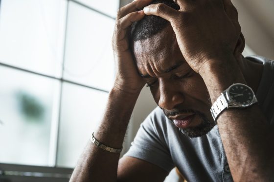 african american man holding his head in discomfort