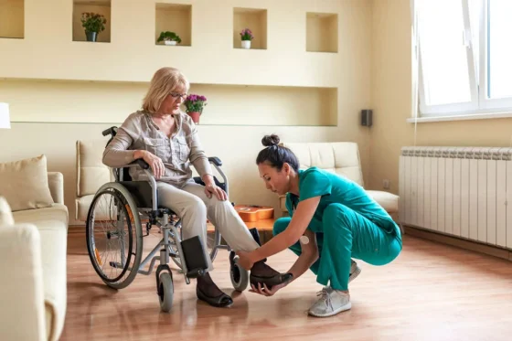 a female support worker putting shoes on a man in a wheelchair