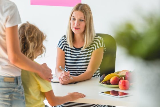 Cute boy and professional dietitian preparing a diet eating plan