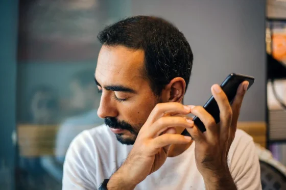 a man with hearing impairment listening close to his phone speaker