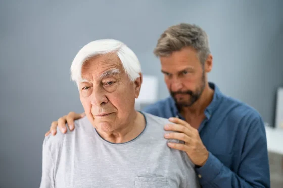 a confused old man being comforted by a male support worker