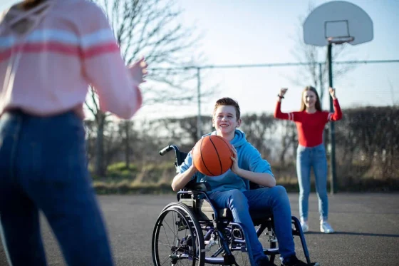 kid in a wheelchair playing basketball outdoors