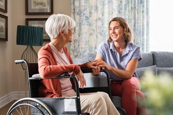a female support worker smiling with an old woman in a wheelchair