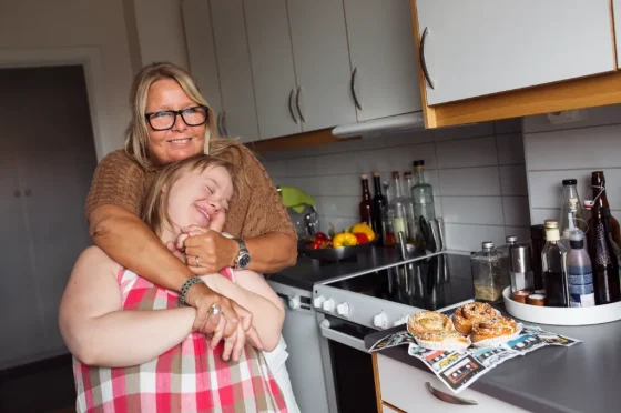 a home carer hugging a smiling down syndrome girl