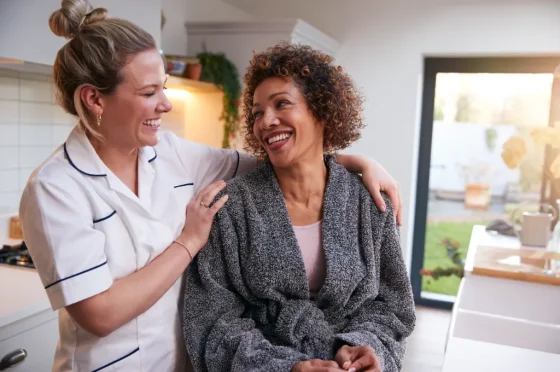 caregiver smiling with an elderly lady at her home