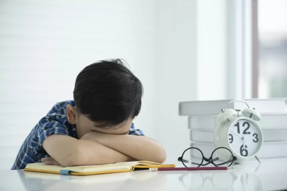 sad boy with his body slouched forward on a school desk