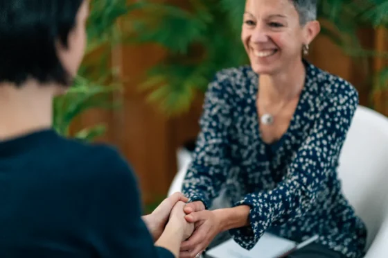 a smiling lady holding hands in content with another lady