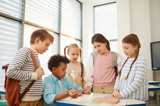 four kids standing next to a boy who is trying to draw something