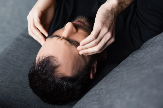 a man laying on a couch holding his head
