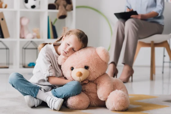 an autistic girl hugging a big teddy bear