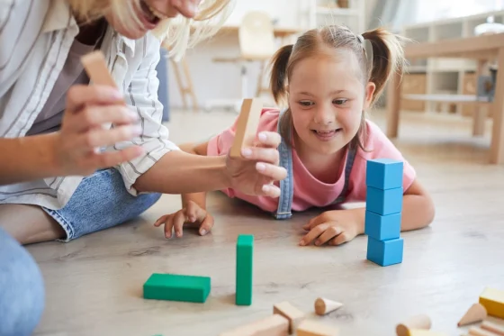 learning support worker playing with blocks with a down syndrome kid
