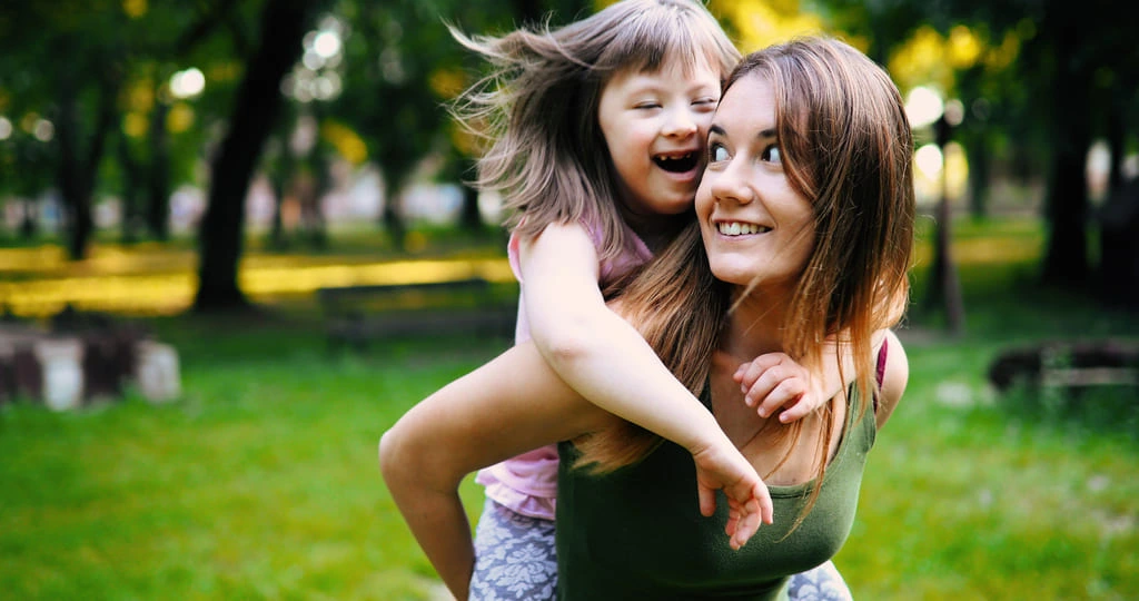 a girl carrying a neurodivergent girl on her back